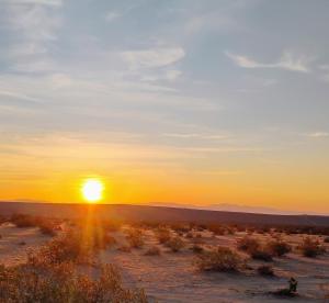 a sunset in the desert with the sun setting at Simply Camping in Hidden River
