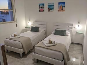 a bedroom with two beds and a ottoman at aMARE21, moderno 2 camere con terrazza privata vista mare in Torre San Gennaro