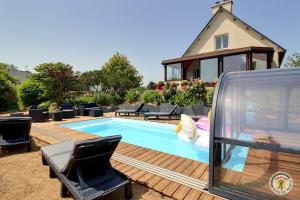 a swimming pool with chairs and a house at La maison d'annie in Pléhédel