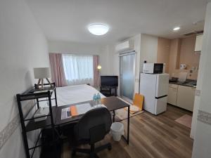 a small room with a bed and a desk and a refrigerator at SABBATH uzumasa 101 in Kyoto