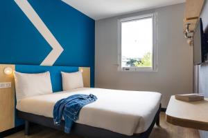 a bedroom with a white bed and a blue wall at Hotel ibis budget Chatillon Paris Ouest in Châtillon