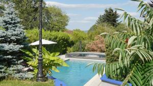 a swimming pool with an umbrella next to a house at Domaine Les Bertrands in Couches