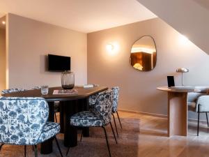 a room with a table with chairs and a mirror at Mercure Maintenon in Maintenon