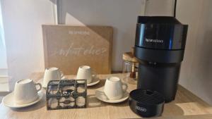 a coffee maker sitting on a table with cups and saucers at La Caverna - Bari Vecchia, Fronte Mare in Bari