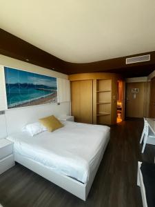 a bedroom with a large white bed with a painting on the wall at SoBlue Hôtel in Antibes