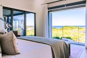 a bedroom with a bed with a view of the ocean at Coastal Cove Whale Watching Retreat in De Kelders