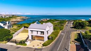 an aerial view of a white house with the ocean at Coastal Cove Whale Watching Retreat in De Kelders