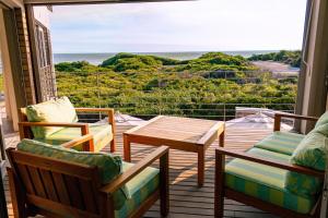 a balcony with chairs and a table and a view of the ocean at Coastal Cove Whale Watching Retreat in De Kelders +33 photos