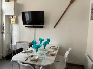 a white table with chairs and a tv on a wall at Chez Tipoulot - maison de pêcheur à 2 pas du port in Fécamp