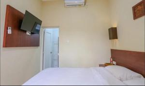 une chambre avec un lit et une télévision au mur dans l'établissement Comfy Room Yogyakarta BY Hamsa Putih, à Yogyakarta