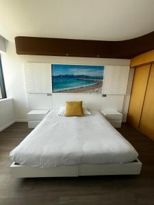a bedroom with a large white bed with a yellow pillow at SoBlue Hôtel in Antibes