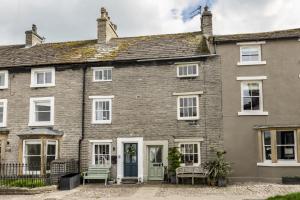 an old brick house with two chairs in front of it at Eldred Cottage in Middleham