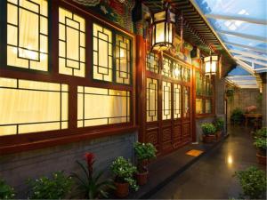 Ein Gebäude mit vielen Fenstern und Pflanzen. in der Unterkunft Beijing Rong Courtyard Boutique Hotel in Peking
