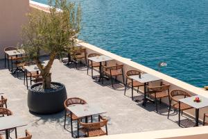 a row of tables and chairs next to the water at Eclectic Syros in Ermoupoli