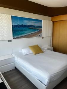 a bedroom with a white bed with a painting on the wall at SoBlue Hôtel in Antibes