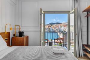 a bedroom with a bed and a balcony with a view at Eclectic Syros in Ermoupoli