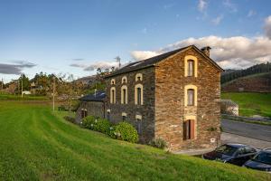 un bâtiment en briques sur une colline avec des voitures garées devant dans l'établissement A Corte, à Trabada