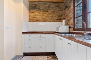 une cuisine avec des armoires blanches et un évier dans l'établissement A Corte, à Trabada 19 autres photos