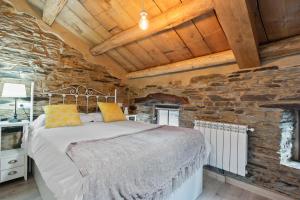 une chambre avec un lit dans un mur de pierre dans l'établissement A Corte, à Trabada
