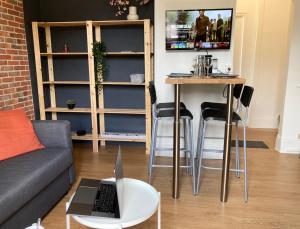 a living room with a couch and a table with a laptop at T2 Home Sweet Home Gare Wifi Parking in Évreux