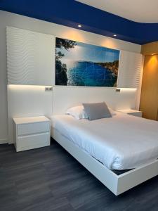a bedroom with a large bed with a painting on the wall at SoBlue Hôtel in Antibes