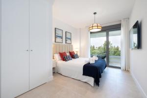 een witte slaapkamer met een bed en een groot raam bij Luxury House Chaparral Golf E12 by AORA STAY in Mijas Costa