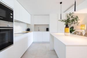 een witte keuken met witte kasten en een vaas met een plant bij Luxury House Chaparral Golf E12 by AORA STAY in Mijas Costa +63 foto's