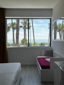 a bedroom with a bed and a large window with palm trees at SoBlue Hôtel in Antibes
