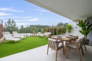 een patio met een tafel, stoelen en gras bij Luxury House Chaparral Golf E12 by AORA STAY in Mijas Costa