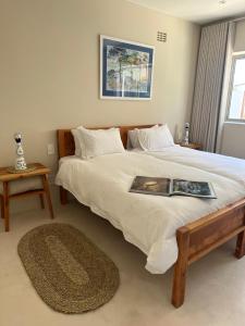 a bedroom with a large bed with a book on it at Sandown Synergy Lagoon House in Hermanus