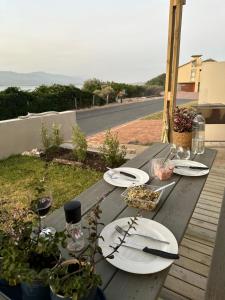 a wooden table with plates of food and wine glasses at Sandown Synergy Lagoon House in Hermanus