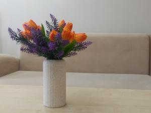 a white vase filled with orange and purple flowers at Лунная Гавань in Aktobe