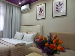 a bedroom with a bed and a vase of flowers at Лунная Гавань in Aktobe