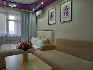 a living room with a couch and a table with flowers at Лунная Гавань in Aktobe