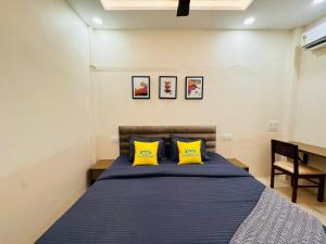 a bedroom with a bed with two yellow pillows at Home Escape 2BHK Retreat Pvt Home in Ujjain