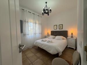 a bedroom with a white bed and a chandelier at Villas Dehesa Roche Viejo in Conil de la Frontera