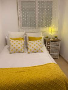 a bedroom with a bed with yellow sheets and pillows at Condado de Alhama Jardin 11 SV51 in Alhama de Murcia