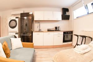 a kitchen with white cabinets and a black refrigerator at Cozy Condo in Tresnjevka in Zagreb