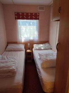 a small room with two beds and a window at Mobil Home 3 chambres au Camping Paradis du Quinquis in Clohars-Carnoët