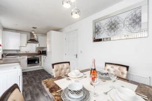 a white kitchen with a table with a bottle of wine at Charming 3 Bedroom Home with Garden near Doncaster in Doncaster