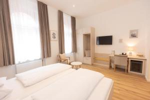 una camera da letto bianca con un letto e una scrivania di Hotel Gollner a Graz