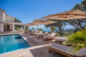 a villa with a swimming pool and umbrellas at Azuréenne de la Nartelle in Sainte-Maxime