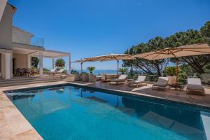 a swimming pool with chairs and umbrellas next to a house at Azuréenne de la Nartelle in Sainte-Maxime