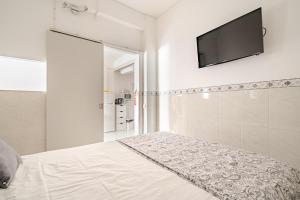 a bedroom with a bed and a flat screen tv on the wall at Silver Coast by Seareen in Armação de Pêra