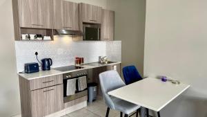 una piccola cucina con tavolo e piano di lavoro bianco di The Bolton Rosebank a Johannesburg