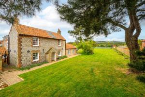 an old brick house with a large grass yard at Old Posting in Brancaster
