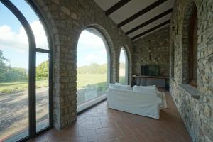 sala de estar con ventanas arqueadas y sofá blanco en Tenuta d'Elci - Relax e Piscina nel Bosco, en Casteldelci