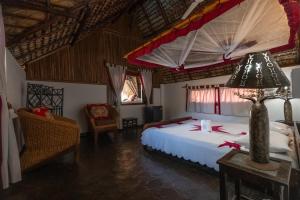 a bedroom with a bed and a lamp on a table at Villa Valiha Boutique Hotel in Madirokely +135 photos