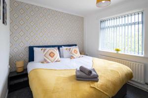 a bedroom with a bed with a yellow blanket and a window at Spacious & Bright 3 Bedroom House in St Helens in Burtonwood