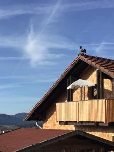 a wooden house with a balcony on the roof at Ferienwohnung Dorfblick (Herzog) in Lindberg
